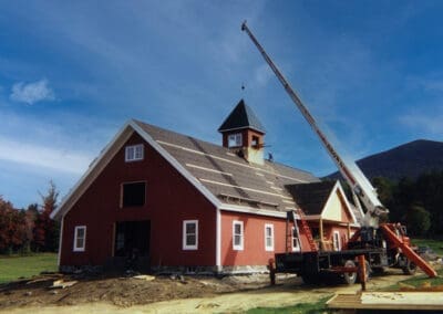 Barn under construction with crane placing cupola