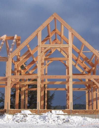 Construction of a timber frame home (D00814 The Mascoma) with snow surrounding it.