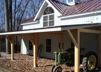 White barn with red metal roof and old John Deere tractor parked in front