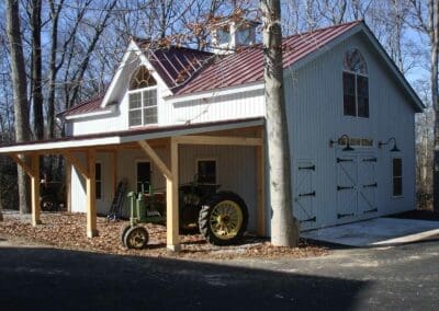 White barn with red metal roof and old John Deere tractor parked in front