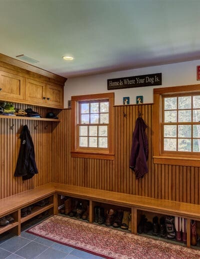 Mud room with wooden cabinets and storage for boots and shoes and other outdoor clothing.