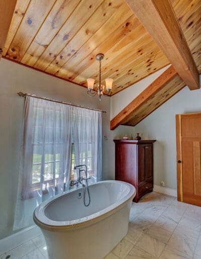 Bathroom featuring sloped wooden ceiling with timber accents.