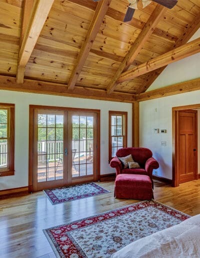 Timber frame bedroom with window seat and double doors out onto deck.