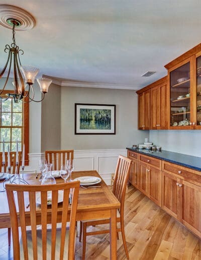 Dining room with long counter and wooden cabinets with two with glass doors.