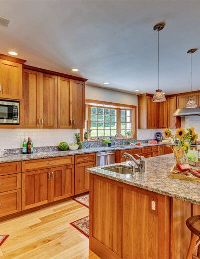 Bright and open kitchen with large island with seating, wooden cabinets and stainless steel appliances