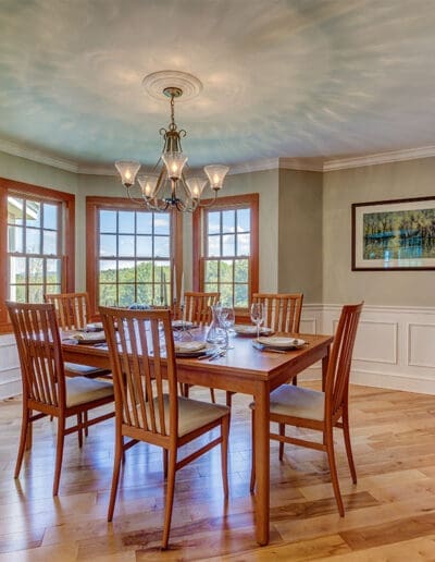 Large, bright dining room with counter and cabinets to the right of a wooden dining table and chairs.