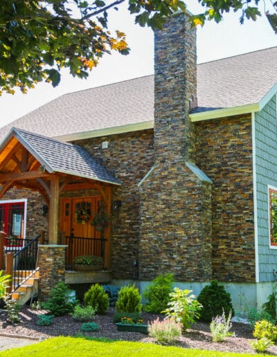 Craftsman's Cottage exterior view of the front with stone facade, blue siding, and red accents