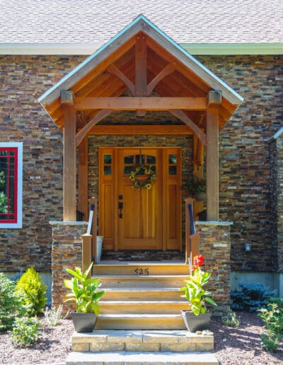 Craftsman's Cottage exterior view of the front with stone facade, blue siding, and red accents