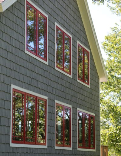 Exterior side of Craftsman's Cottage with blue siding and red accents around the windows