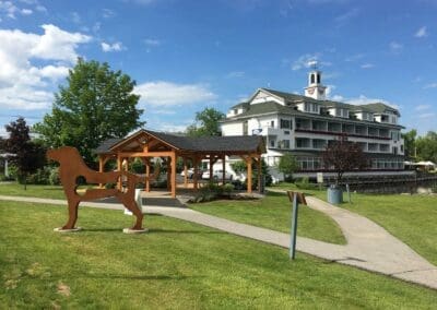 View of Meredith Pavilion from a distance with Mill Falls next to it and dog statue in front